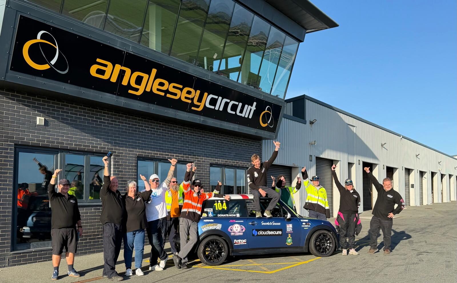 The STS Racing team celebrating beside their number 104 Mini outside the control tower at Anglesey Circuit.