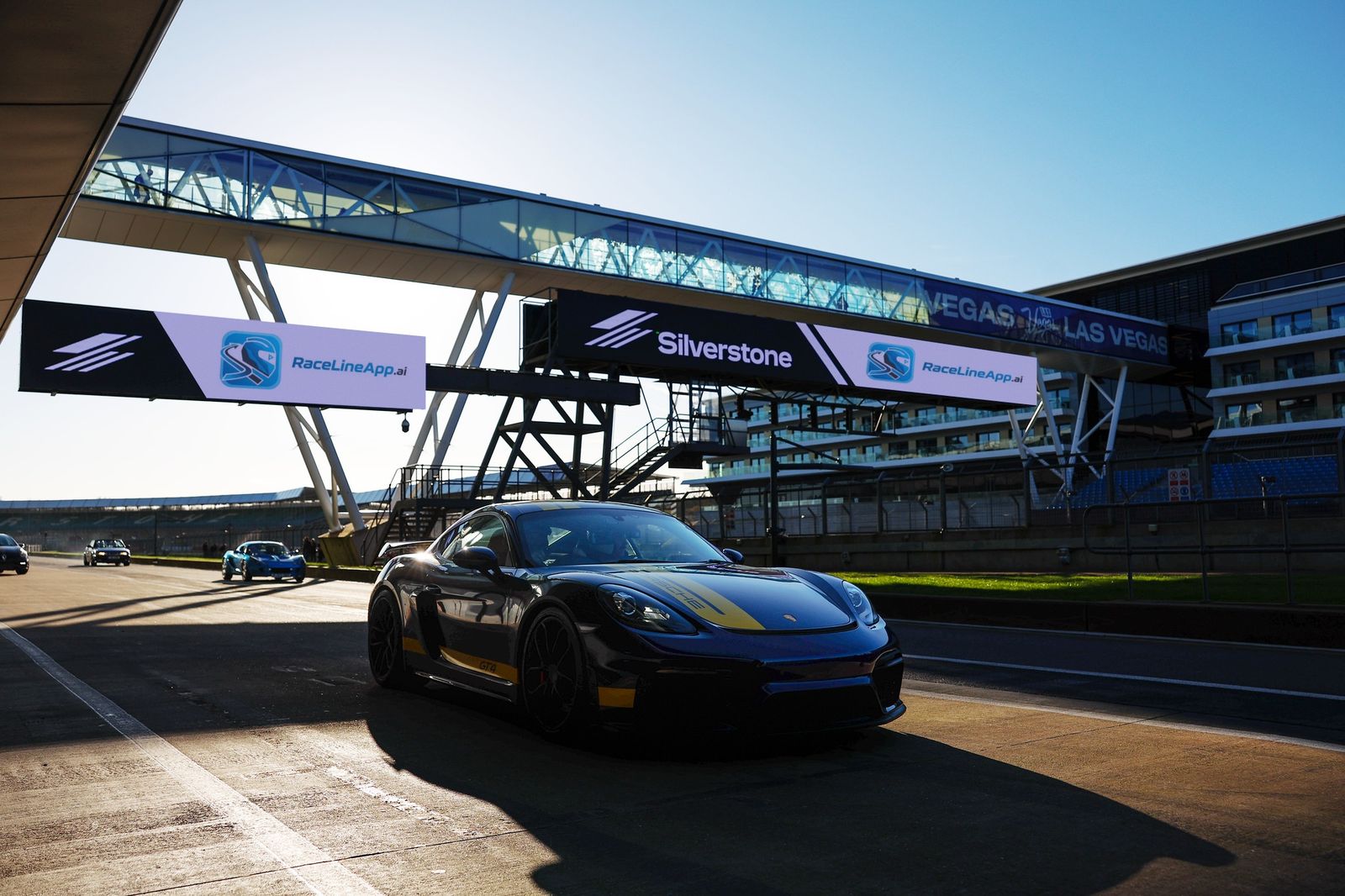 A Porsche 718 GT4 in the Silverstone pit lane, with the RaceLineApp.ai gantry as it will look on beta day